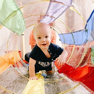 Baby crawling through colorful tunnel